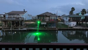 A waterfront property with a dock, a pool with green lighting, and houses with balconies. - This island canal home provides beautiful views and amazing sunsets! (Freeport)