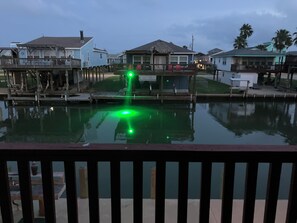 A waterfront property with a dock, a pool with green lighting, and houses with balconies. - This island canal home provides beautiful views and amazing sunsets! (Freeport)