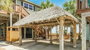 A wooden gazebo with a thatched roof, a wooden bench, and a staircase leading to a deck. - This island canal home provides beautiful views and amazing sunsets! (Freeport)