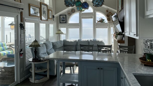 A kitchen with a large island, white cabinetry, and a view through the windows. - Sandbridge Beach, Coastal Chic Back Bay Waterfront Tiny Home! (Virginia Beach)