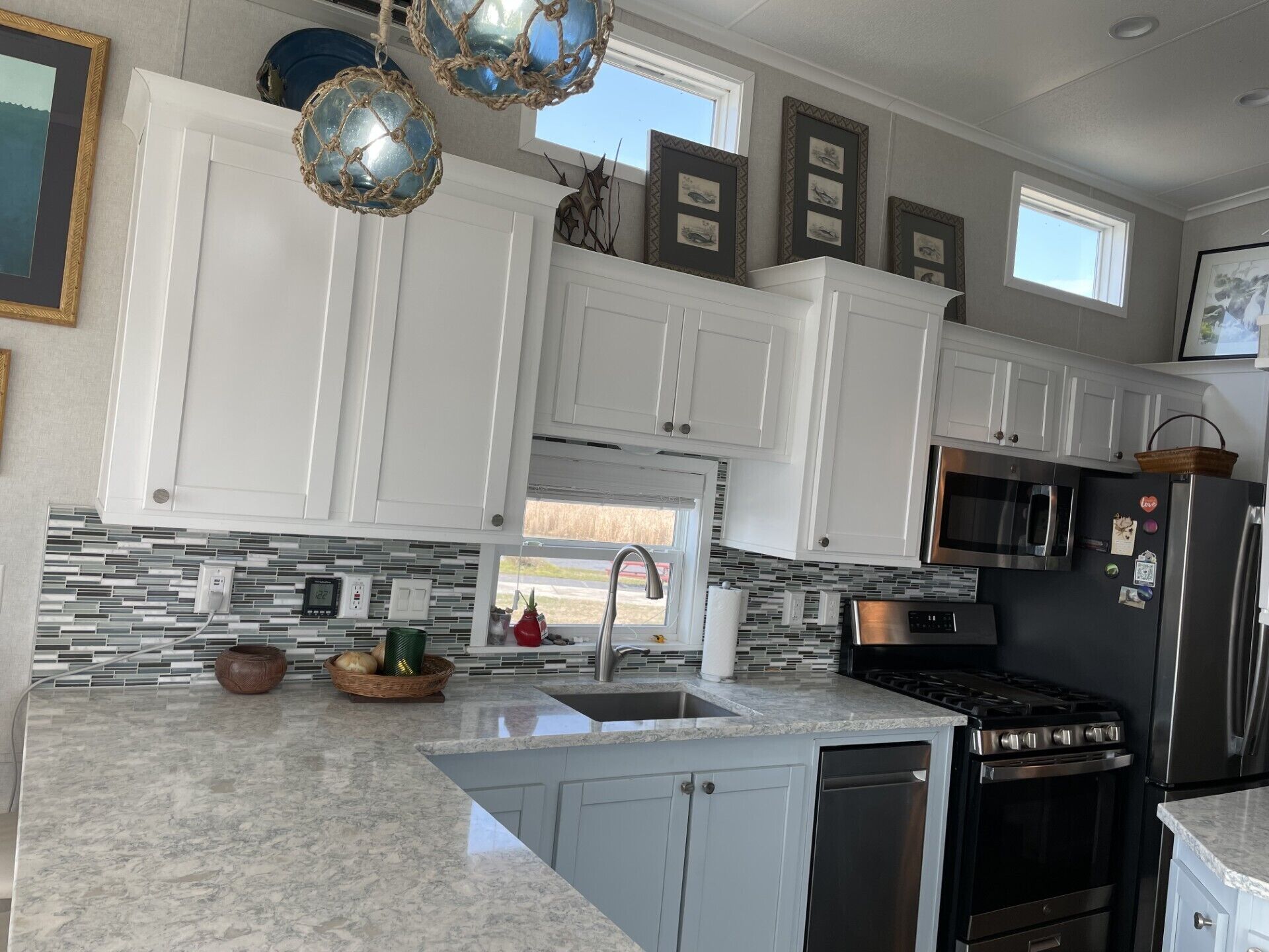 Una cocina moderna con gabinetes blancos, un refrigerador de acero inoxidable, una estufa y un salpicadero de azulejos.