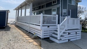 A coastal house with a covered porch, a staircase, and a view of the ocean. - Sandbridge Beach, Coastal Chic Back Bay Waterfront Tiny Home! (Virginia Beach)