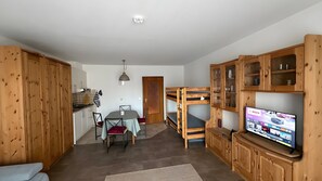 Ein kompakter Wohnraum mit Küchenzeile, Essbereich, Etagenbetten und einem Fernseher.