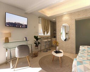 Habitación de hotel moderna con un escritorio de vidrio, una silla cómoda, un tapete redondo, una cama con cubrecama de estampado geométrico, un espejo grande y un televisor que muestra un paisaje urbano.