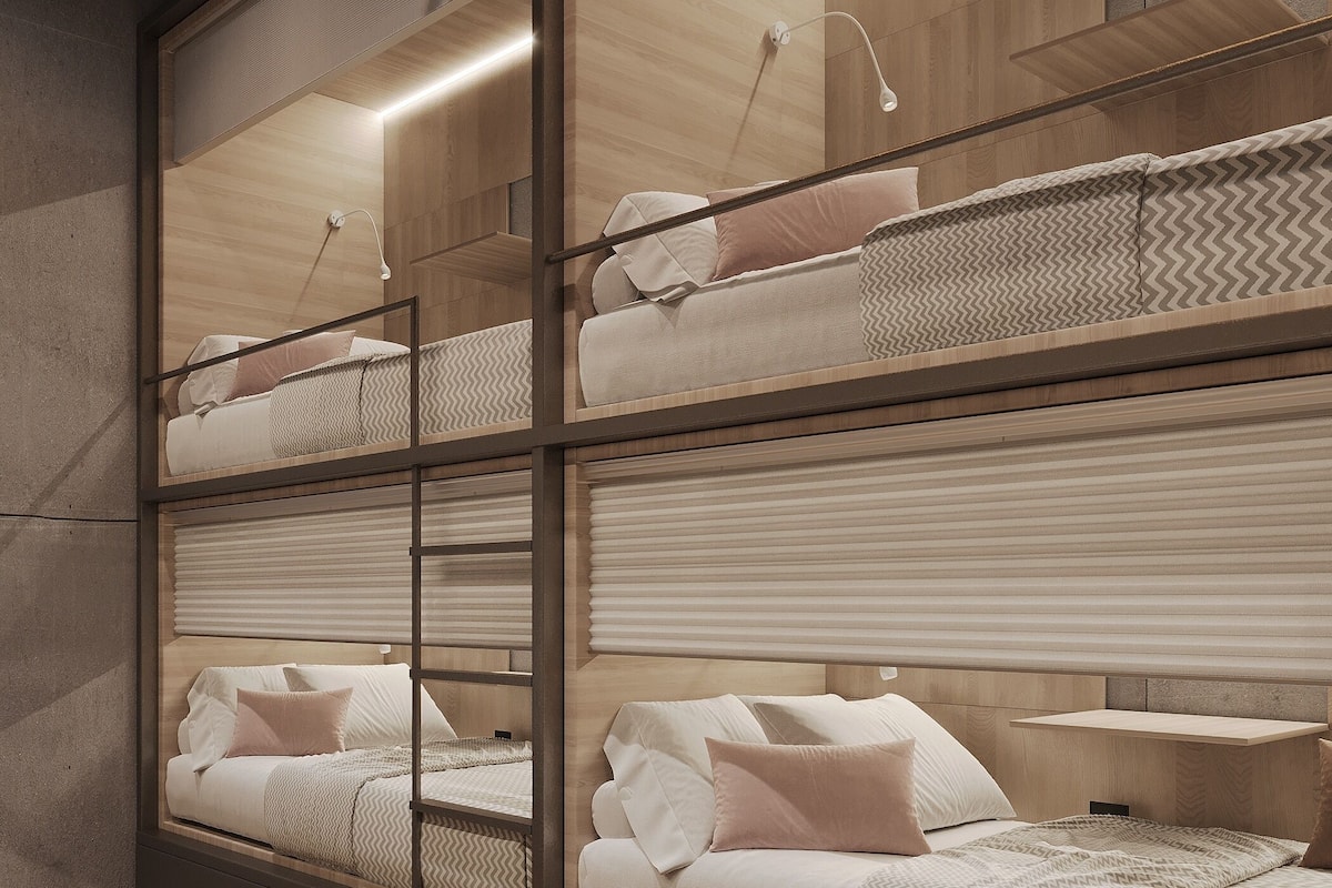 A modern hotel room with bunk beds, a bedside table, and a lamp.