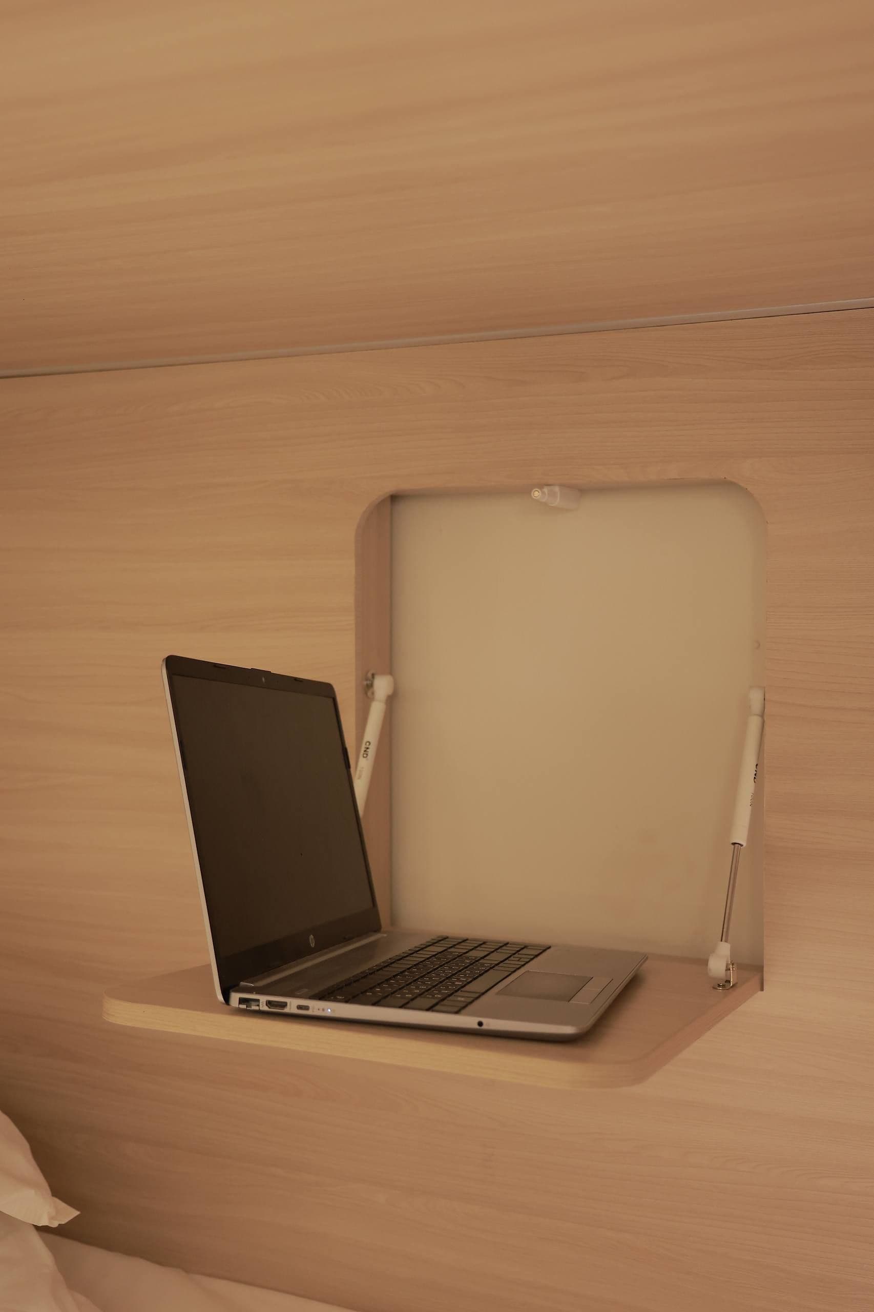 A laptop on a wooden desk with a chair.