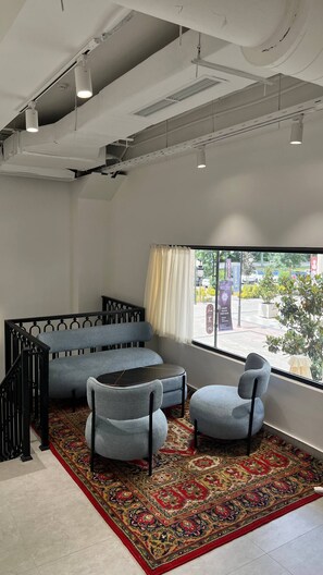 A modern room with a sofa, two armchairs, a patterned rug, and a large window with a view of the outside. - PREMIUM DOO Hostel (Tashkent)