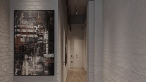 A hallway with a large abstract painting on the left, wooden flooring, and white brick walls. - PREMIUM DOO Hostel (Tashkent)