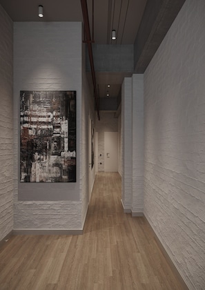 A hallway with a large abstract painting on the left, wooden flooring, and white brick walls. - PREMIUM DOO Hostel (Tashkent)