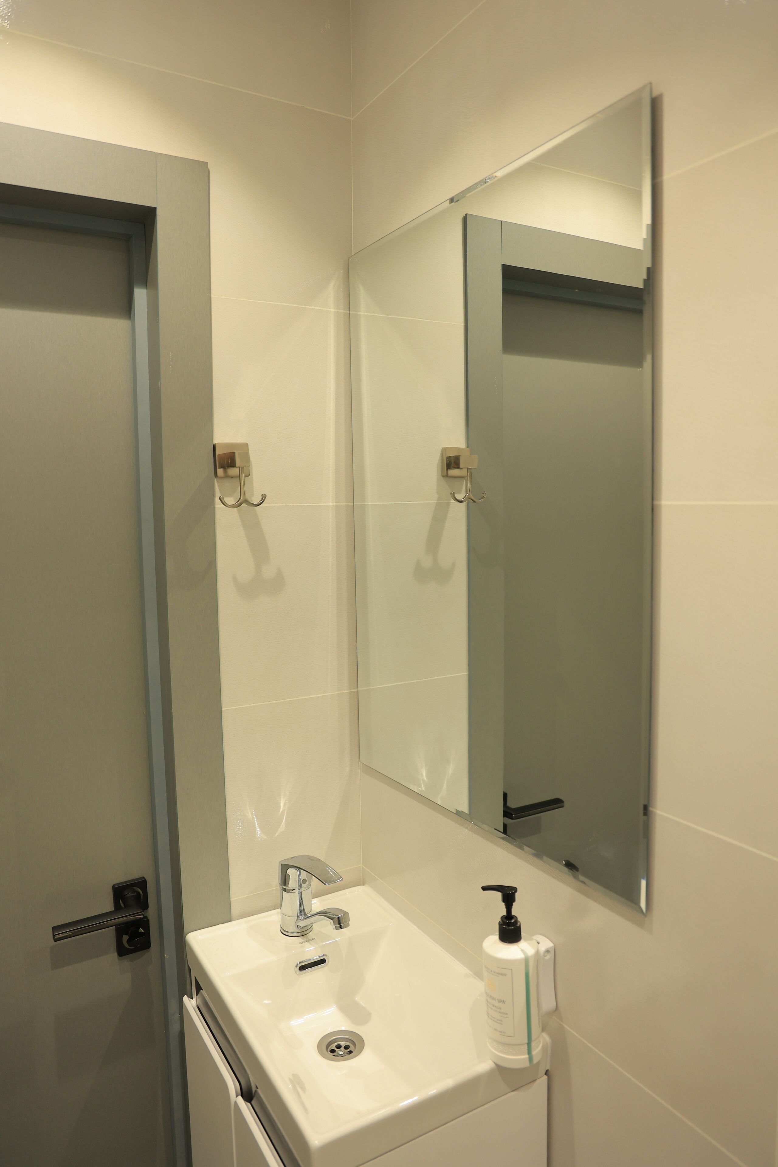 A bathroom with a white sink, a mirror, and a towel rack.