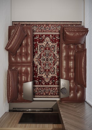 A room with a large, brown leather sofa, a patterned rug, and a modern TV stand.