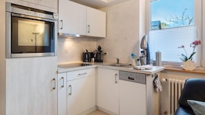 Uma cozinha compacta com forno embutido, máquina de lavar louça e janela com vista para o exterior.