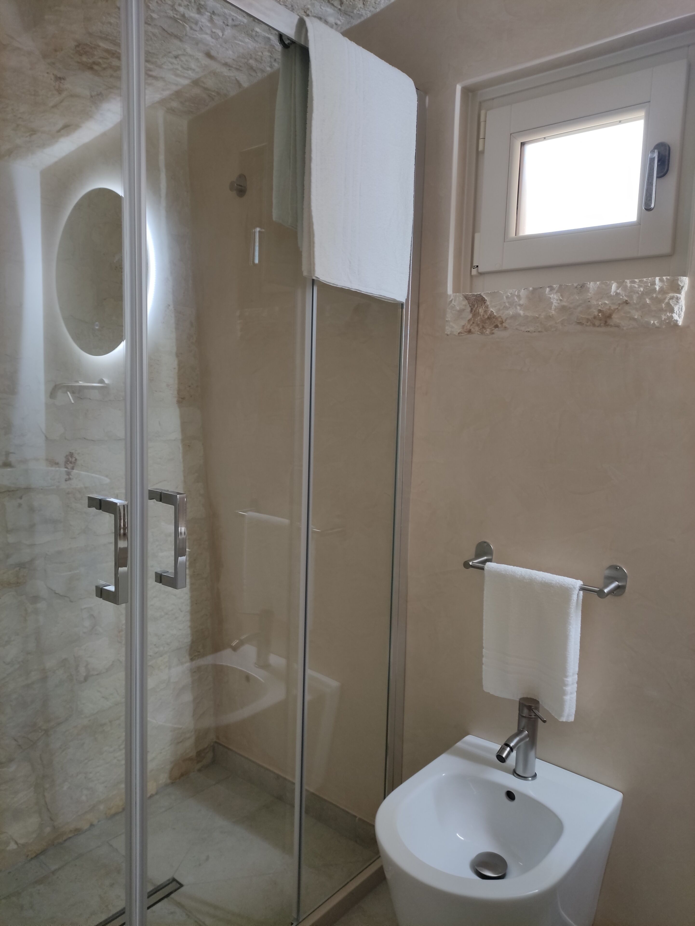 Une salle de bain avec une douche à parois de verre, un lavabo blanc et un porte-serviettes.