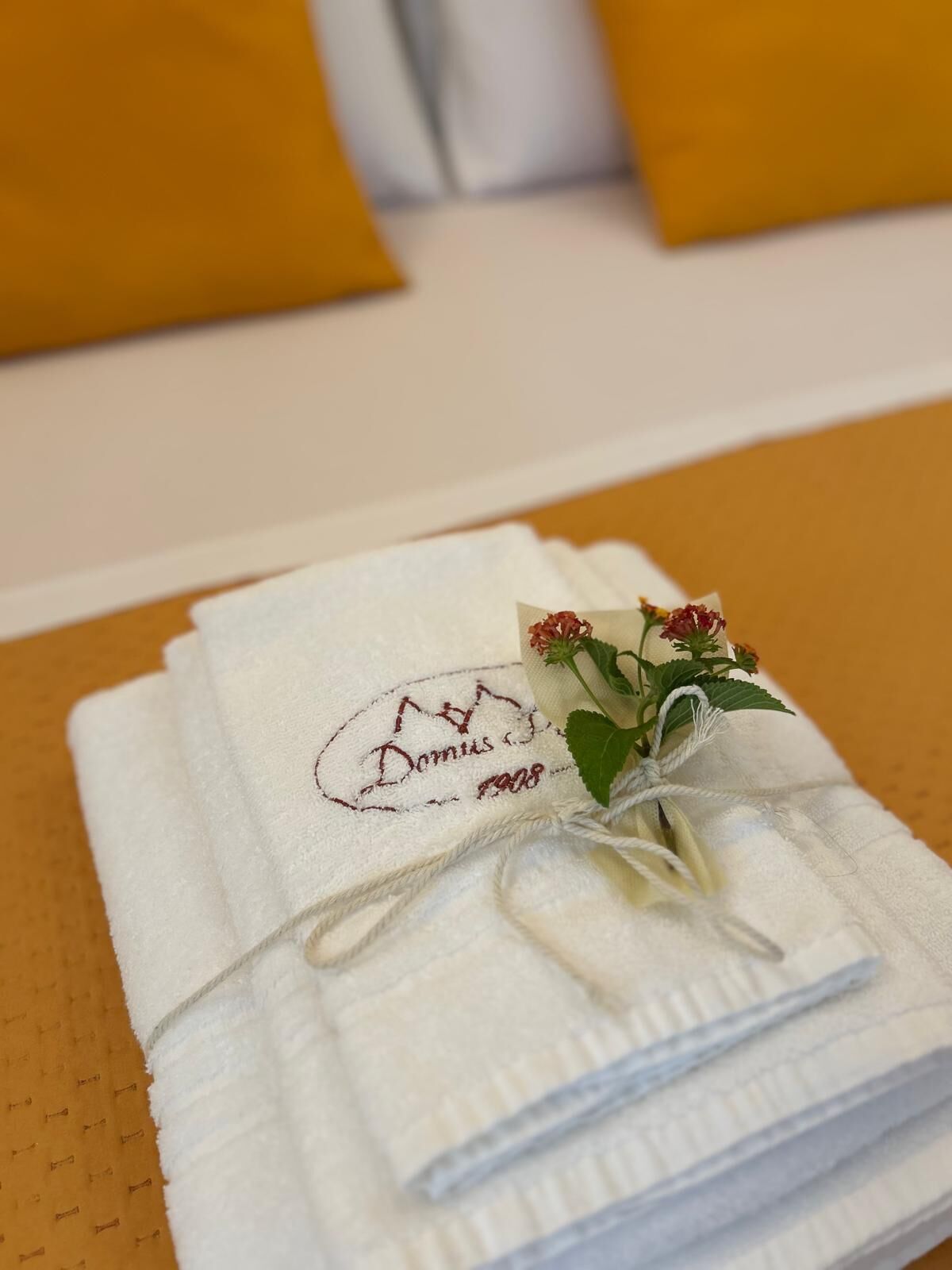 Une pile de serviettes blanches ornées de motifs brodés et d’une petite décoration florale.