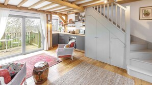 Una cocina amplia con techo de madera, un área de comedor con sofá rojo, y una escalera que conduce a un nivel superior.