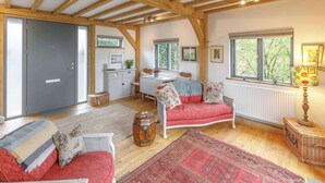 Una habitación con techo de madera, un sofá rojo, una mesa blanca y una ventana con vista a árboles.