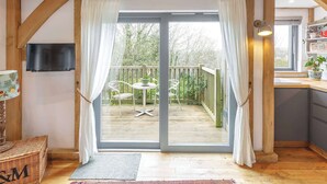Una habitación con estructura de madera y una puerta corrediza de vidrio que da a una terraza exterior con sillas y una mesa.