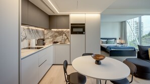 A modern kitchen with a marble backsplash, a microwave, and a dining area with a round table and chairs. - Areeiro Vision Studio by Homing (Lisbon)