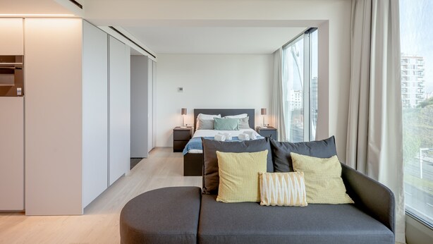 A modern hotel room with a bed, a sofa, and a large window. - Areeiro Vision Studio by Homing (Lisbon)