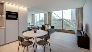 A modern living space with a dining area, sofa, and large windows offering a view of the city. - Areeiro Vision Studio by Homing (Lisbon)