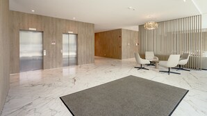 A modern lobby with elevators, a reception area, and a seating area. - Areeiro Vision Studio by Homing (Lisbon)