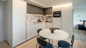 A modern kitchen with a marble backsplash, a round dining table with chairs, and a built-in oven. - Areeiro Vision Studio by Homing (Lisbon)