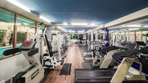 Une salle de sport équipée de tapis de course, d’appareils de musculation et de poids libres.