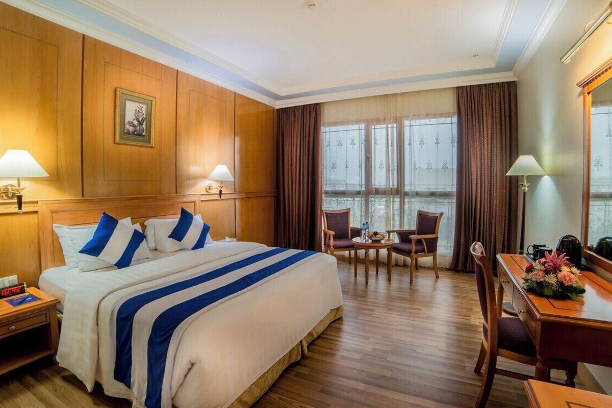 A hotel room with a large bed, two bedside tables, a desk, and a chair.