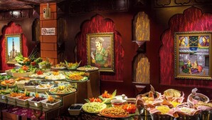 Un buffet proposant divers plats, des œuvres d’art encadrées accrochées aux murs et un panneau indiquant qu’il est interdit de fumer.