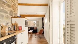 Eine Küche mit Steinwand, Holzbalken und einer Essecke mit Sofa und Tisch.
