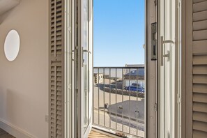 A balcony with a view of a parking area and a building with stone walls.