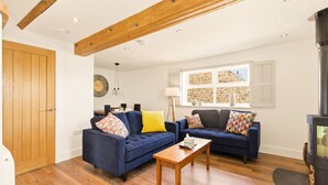 Ein Wohnzimmer mit zwei blauen Sofas, einem Holztisch, einem Kamin und einem Fenster mit Rollläden.