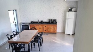 A modern kitchen with wooden cabinets, a dining table with chairs, and a sofa with cushions. - Maktub House and Leisure Area Temporada Delfinopolis. Cozy space. (Delfinópolis)