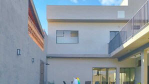 A swimming pool with a rainbow float, lounge chairs, and a building with a balcony. - Maktub House and Leisure Area Temporada Delfinopolis. Cozy space. (Delfinópolis)