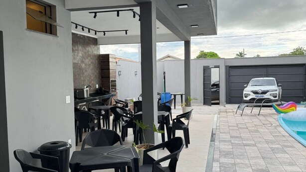 An outdoor patio area with tables and chairs, a pool, and a car parked nearby. - Maktub House and Leisure Area Temporada Delfinopolis. Cozy space. (Delfinópolis)