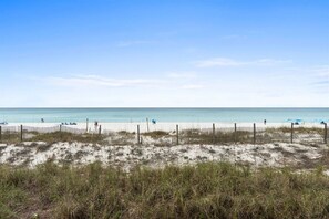 A beach with a sandy foreground, a wooden fence, and a clear blue sky. - Beach View 2BR | Walk to Beach & Dining | Sleeps 6 (Panama City Beach)