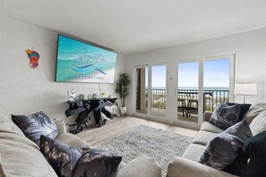 A living room with a large window, a sofa, a coffee table, and a painting. - Beach View 2BR | Walk to Beach & Dining | Sleeps 6 (Panama City Beach)