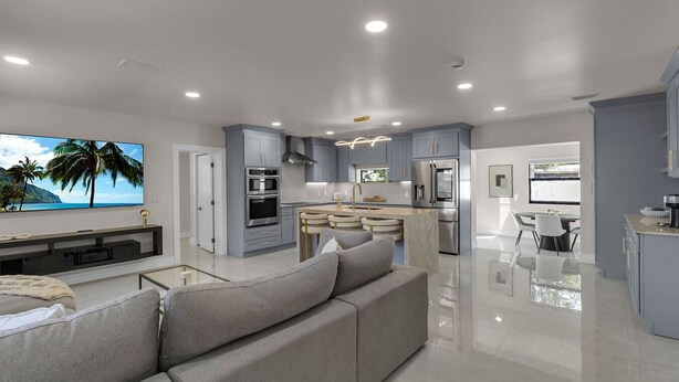Una cocina moderna con una isla central, electrodomésticos integrados y un comedor con mesa y sillas.