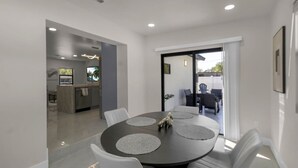 Un comedor moderno con una mesa redonda, sillas blancas y vistas al patio exterior.
