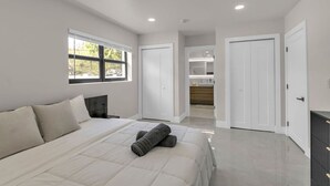 Un dormitorio moderno con una cama grande, una mesita de noche, una ventana y vistas al baño.