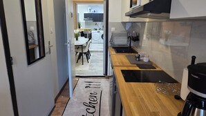A modern kitchen with a wooden countertop, a black range hood, and a black pendant light. - Chambre Autonome Tout Confort with Kitchenette (Roubaix)