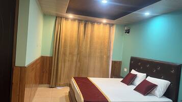 Ein Hotelzimmer mit einem Bett mit Holz-Kopfteil, einer roten Bettdecke und einem Vorhang.