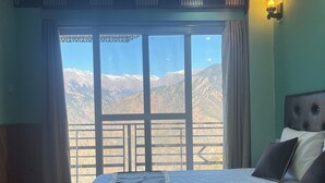 Ein Zimmer mit Bett, Bergblick und einem Balkon.