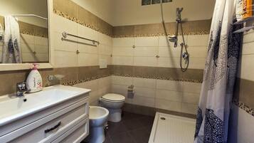 Un baño con lavamanos blanco, inodoro, ducha y espejo.