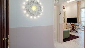 Ein modernes Wohnzimmer mit Flachbildfernseher, einem Essbereich mit Tisch und Stühlen sowie einer dekorativen Wandleuchte.