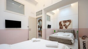 Ein Schlafzimmer mit einem Bett, einem Fernseher, einem Spiegel und einer Tür zu einem Badezimmer.