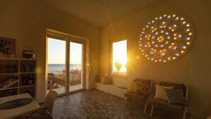 Een kamer met een groot raam, een ronde lamp en uitzicht op zee.
