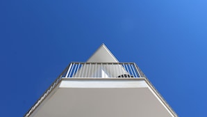 Een gebouw met een puntdak en een balkon met metalen hekwerk.