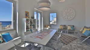 Een moderne woonkamer met een groot raam, een eettafel en een bank.