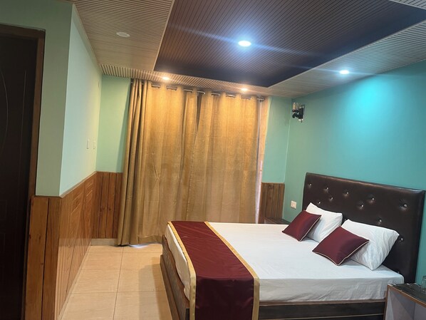 A hotel room with a wooden headboard bed, a red bedspread, and a curtain.